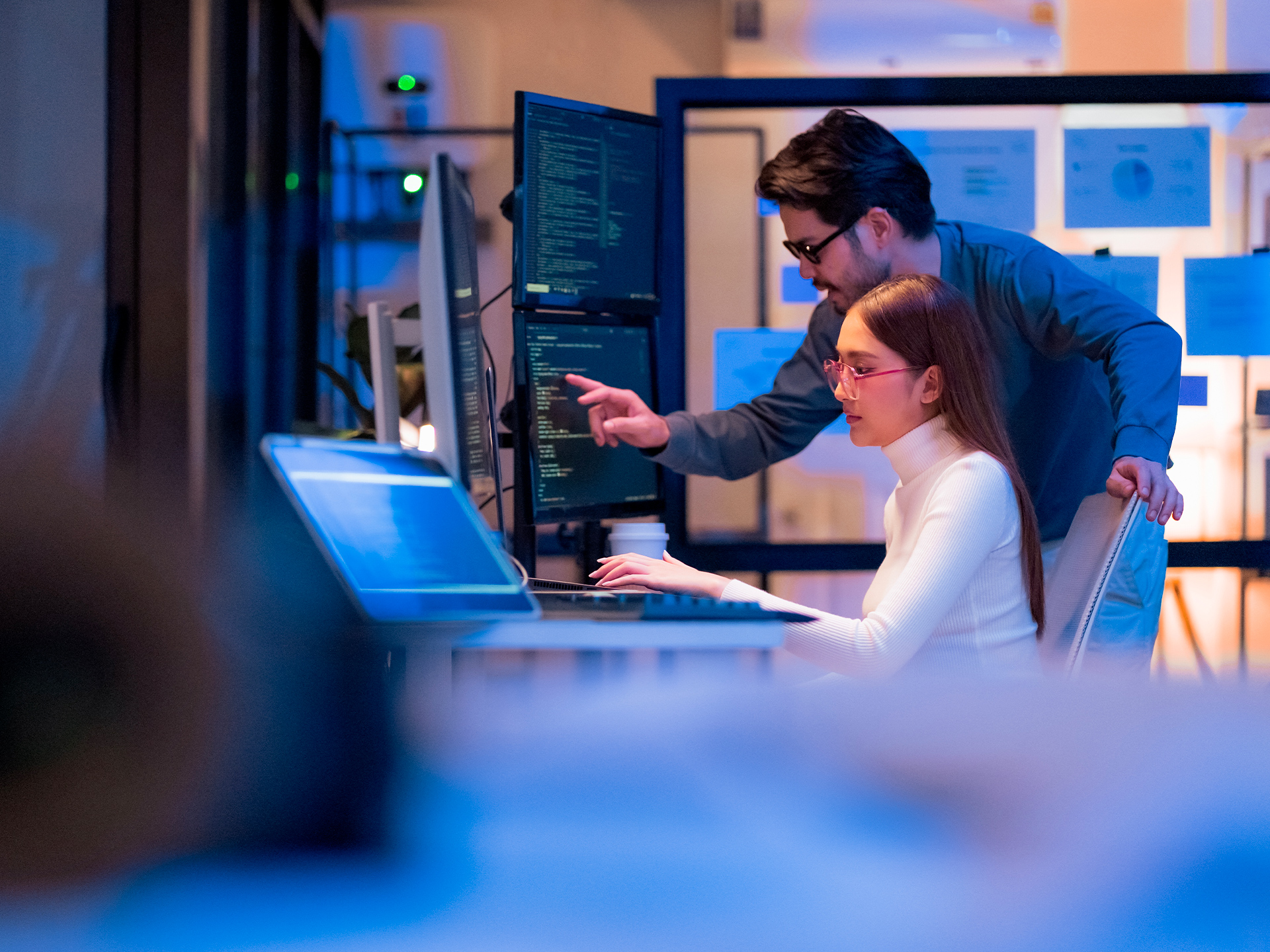 IT specialists coding and reviewing data on multiple monitors