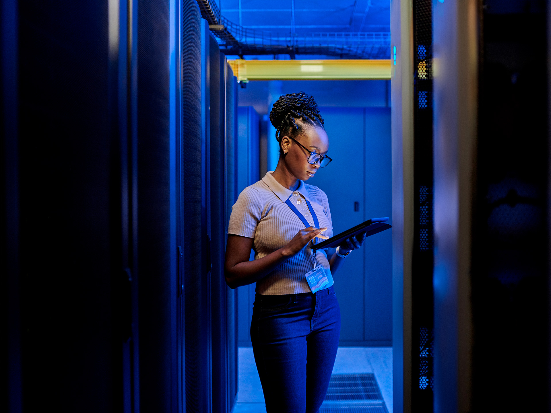 IT professional using tablet in data center with blue server infrastructure
