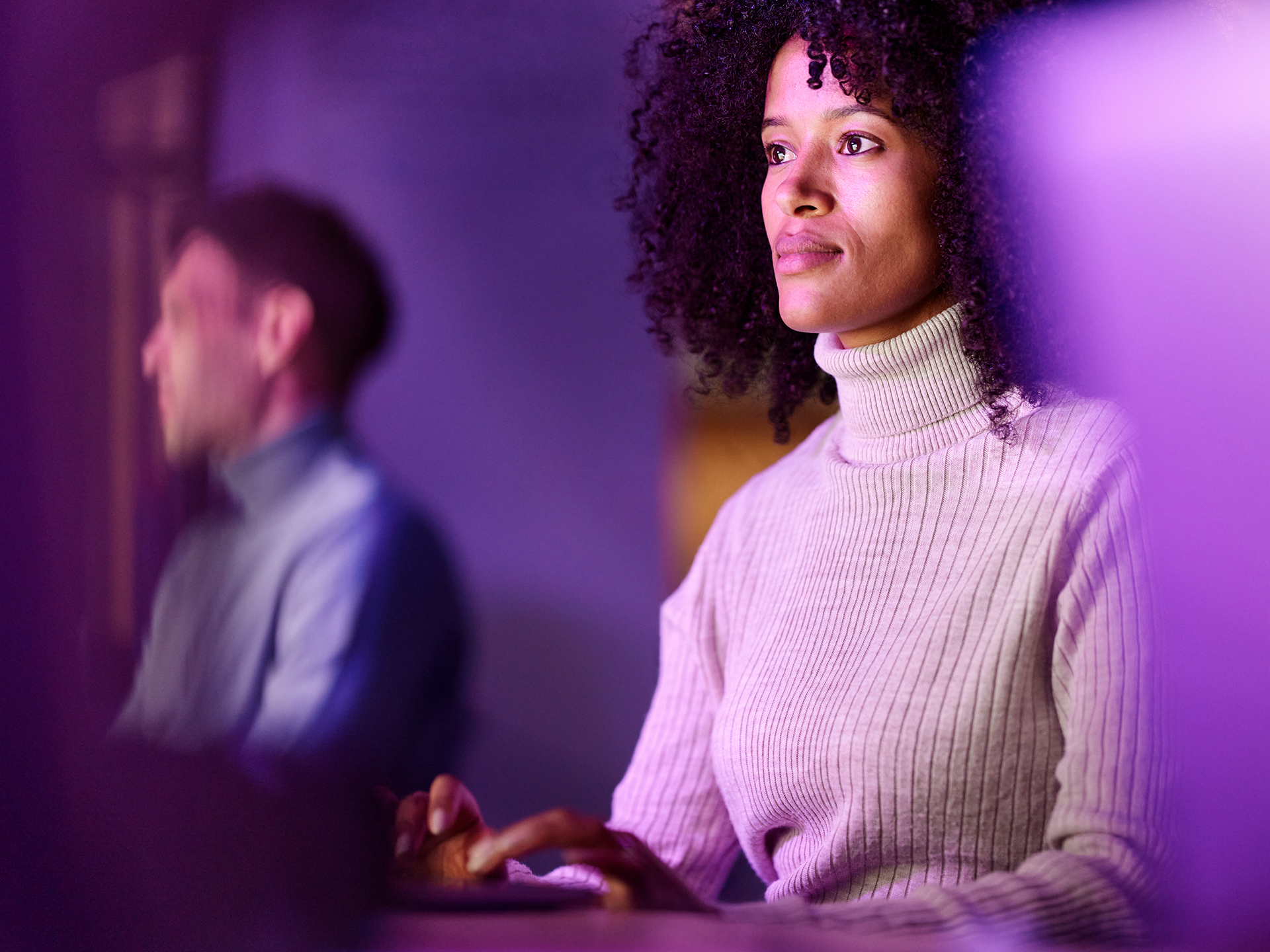 Person using computer in low light workspace with colored lighting