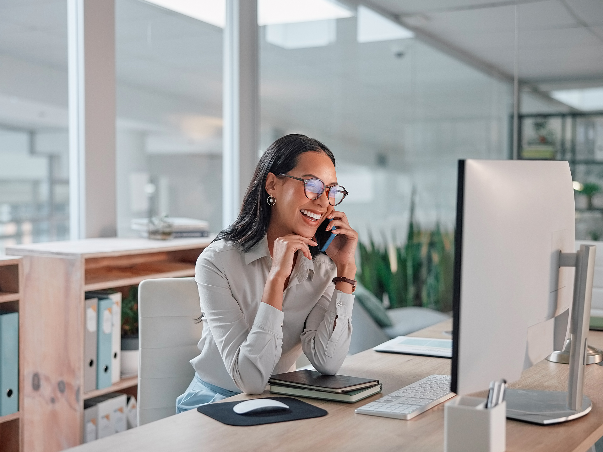 Person speaking on phone while seated at desk with desktop computer