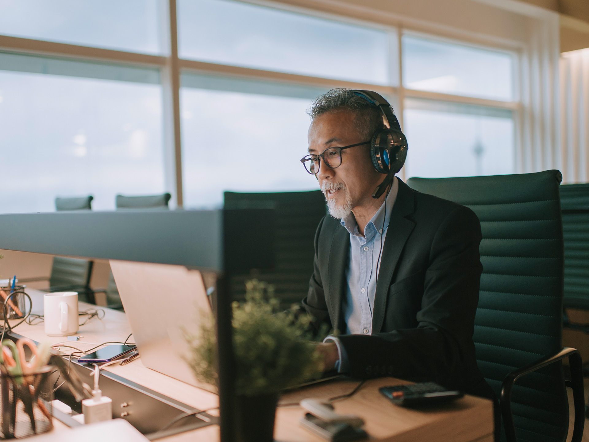 Person using laptop with headset at desk in office