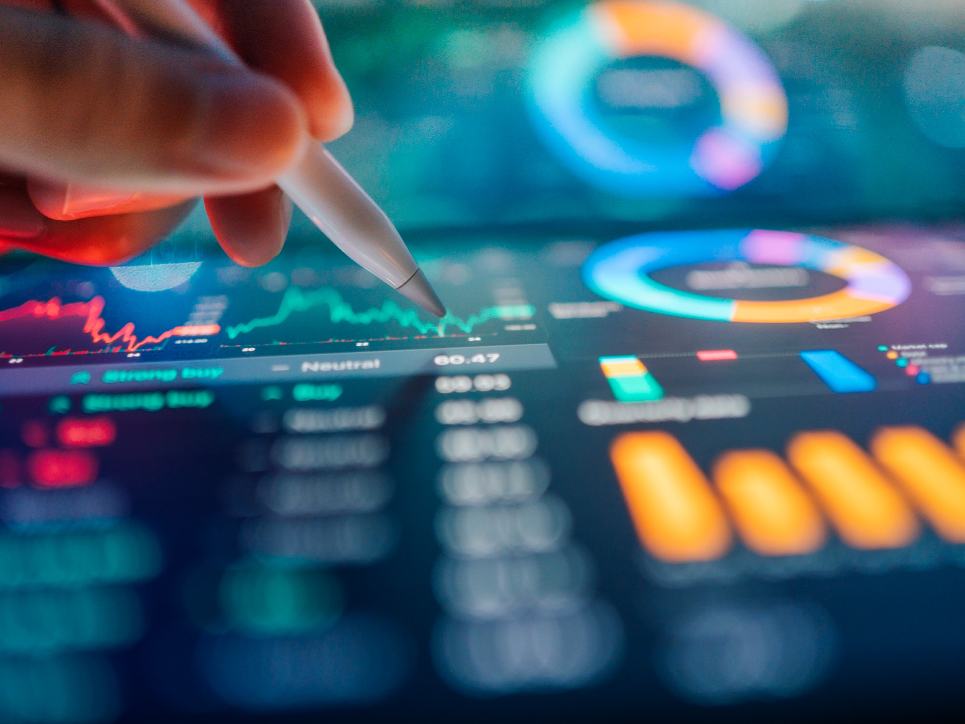Hand using stylus on digital financial dashboard with charts