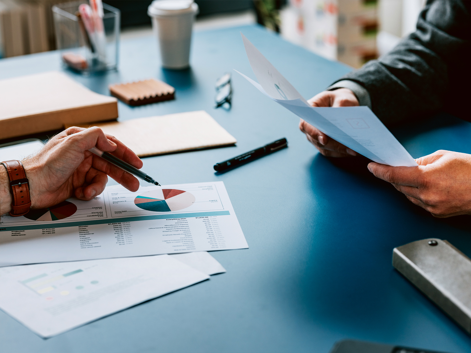 Hands pointing at data charts and documents on desk