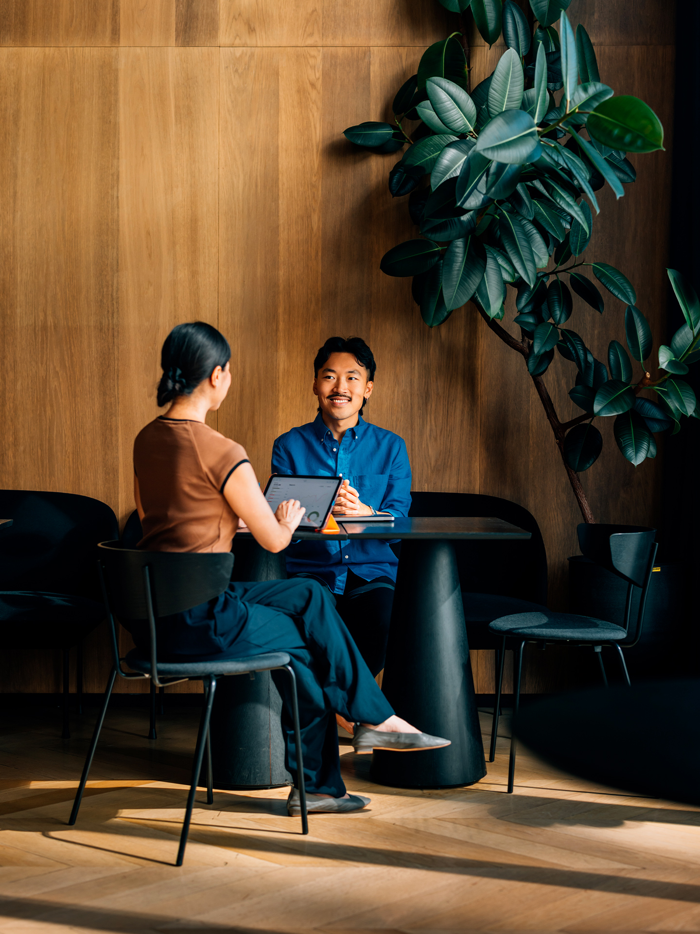 Two people sitting and using tablet in office lounge