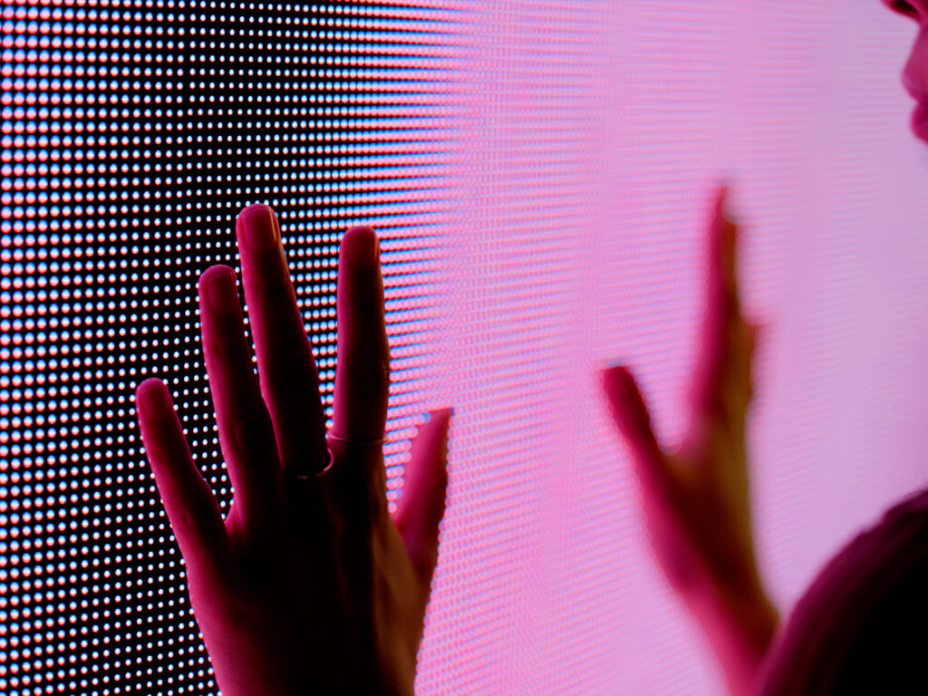 Hand interacting with digital screen interface with light patterns