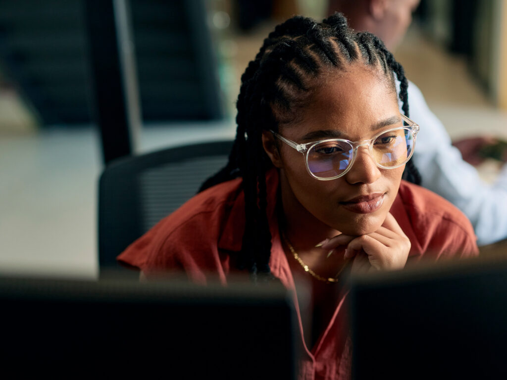 Person using laptop at table in bright open workspace