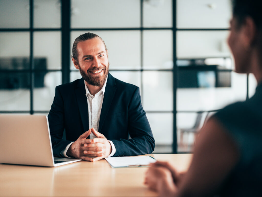 Two people in discussion across table with laptop in office